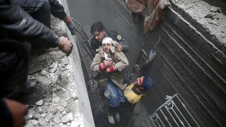 Syria Civil Defence members help an unconscious woman from a shelter in the besieged town of Douma, Eastern Ghouta, Damascus, on February 22, 2018.
