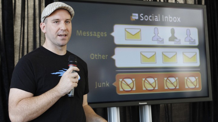 Andrew Bosworth speaks into a microphone in front of a screen.