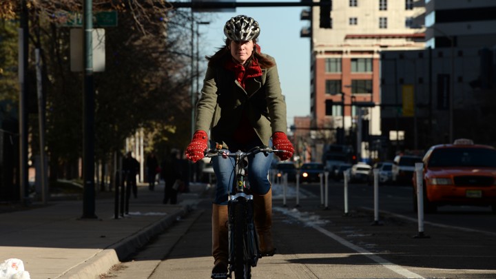 A woman rides a bicycle down a bike lane in Denver