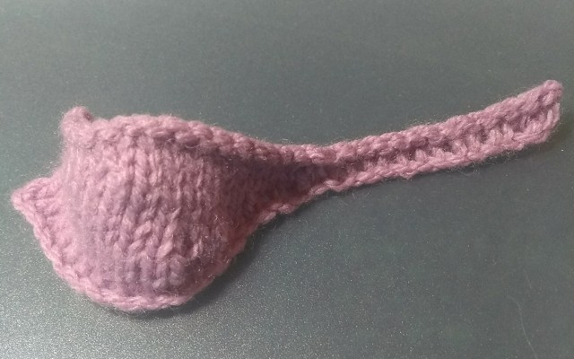 A pink knitted object resembling a ladle