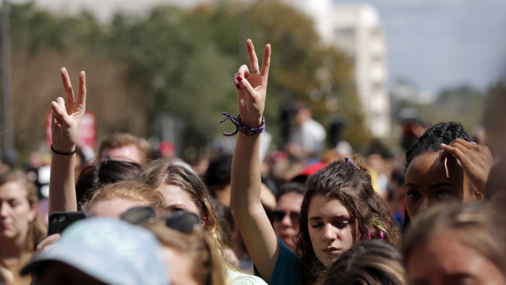 People raise their hands in peace signs at a rally.