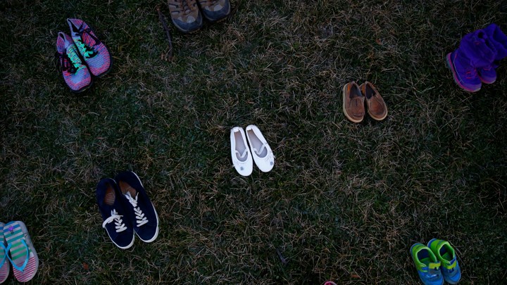 Pairs of shoes arranged in rows on grass