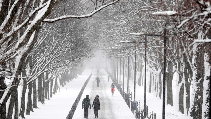 People walk down a path on the National Mall during a snowstorm.