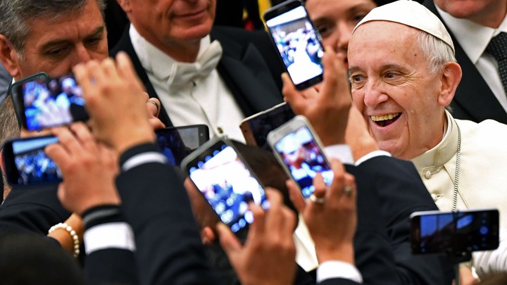 Pope Francis arrives to lead his weekly general audience in 2016 at the Vatican as people take pictures of him.