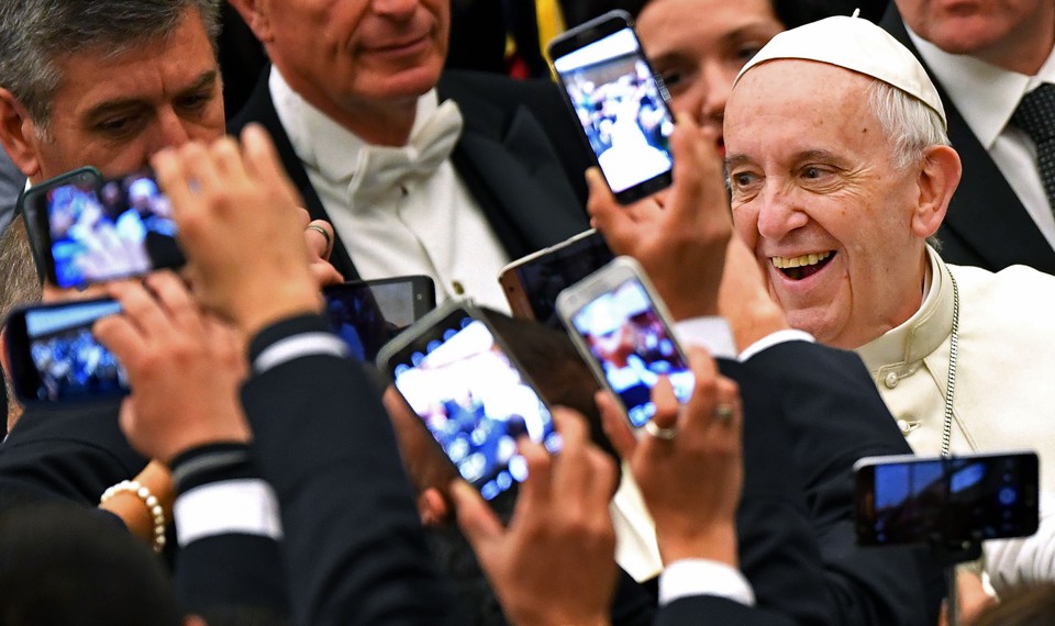 Pope Francis arrives to lead his weekly general audience in 2016 at the Vatican as people take pictures of him.