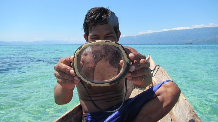 A Bajau diver holds up his wooden diving mask.