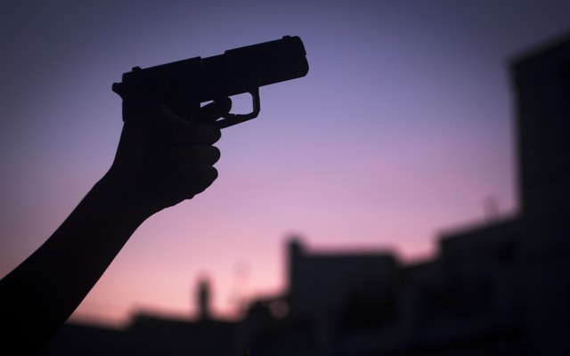 A hand in silhouette holding a shotgun