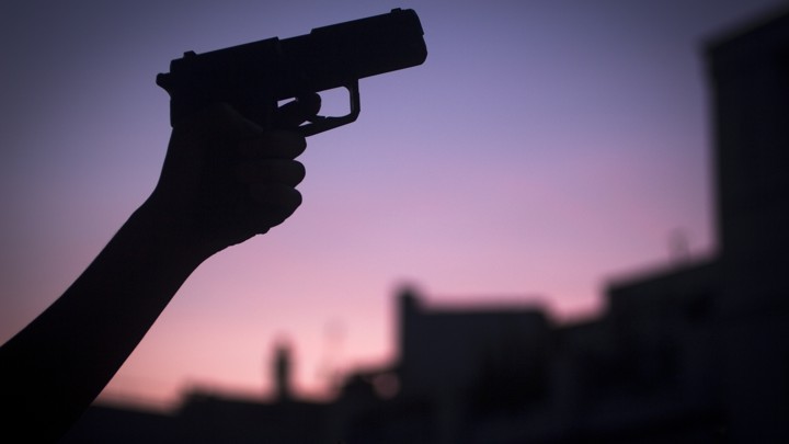 A hand in silhouette holding a shotgun