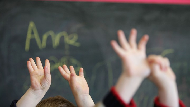 Children's hands in the air in front of a chalkboard
