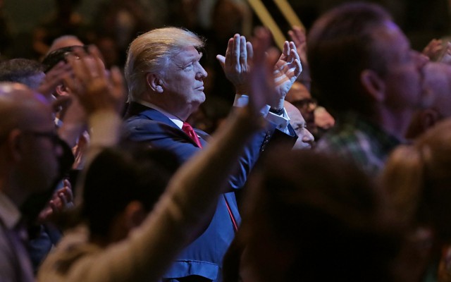Donald Trump, standing among a group of churchgoers, claps during a worship service in Las Vegas.