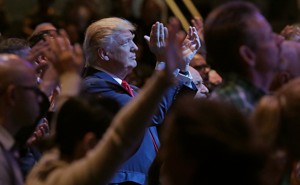 Donald Trump, standing among a group of churchgoers, claps during a worship service in Las Vegas.