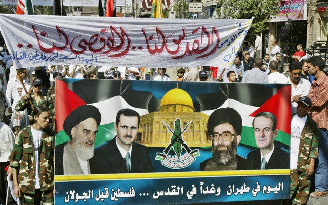 Protestors hold up a banner picturing late Ayatollah Ruhollah Khomeini, Syrian President Bashar al-Assad and Iranian Supreme Leader Ali Khameni and late Syrian Presidnet Hafez al-Assad.
