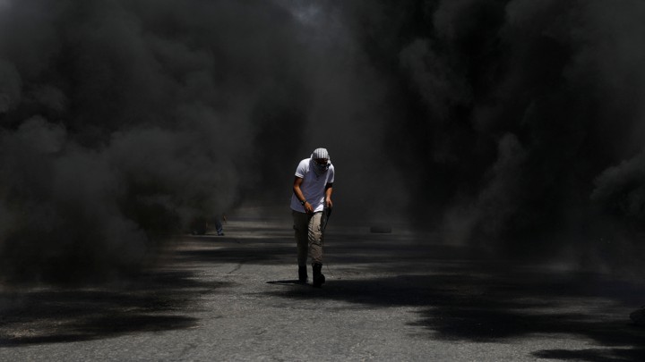 A protester crouching in black smoke