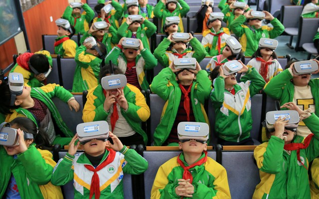 A group of kids in green and yellow school uniforms wearing VR headsets