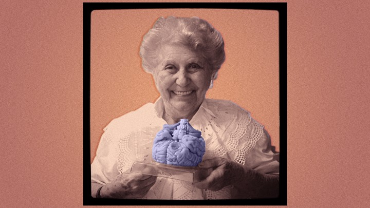 An elderly woman holding a plastic model of a brain