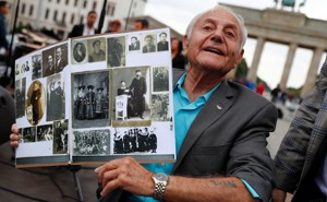 Holocaust survivor Morris Dan shows family photographs as he poses in front of the Brandenburg Gate in Berlin in 2017. 