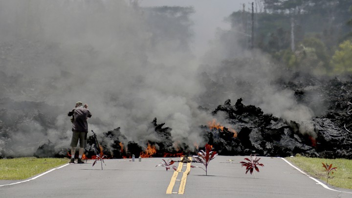 Bundles of leaves lie along a road where lava is moving toward them.