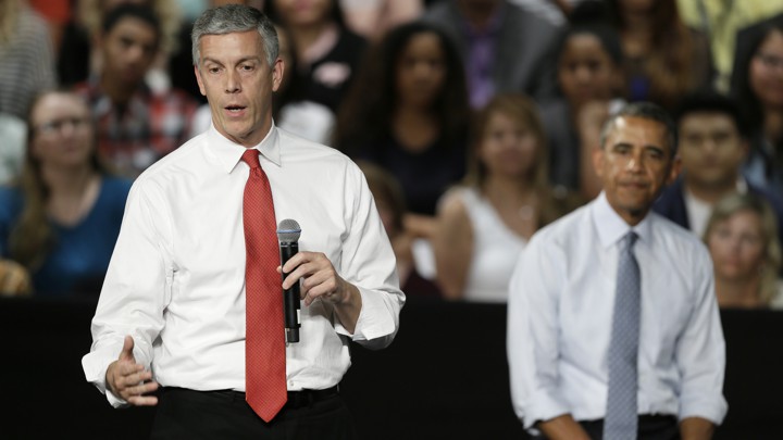 Duncan speaking into a microphone with Obama behind him