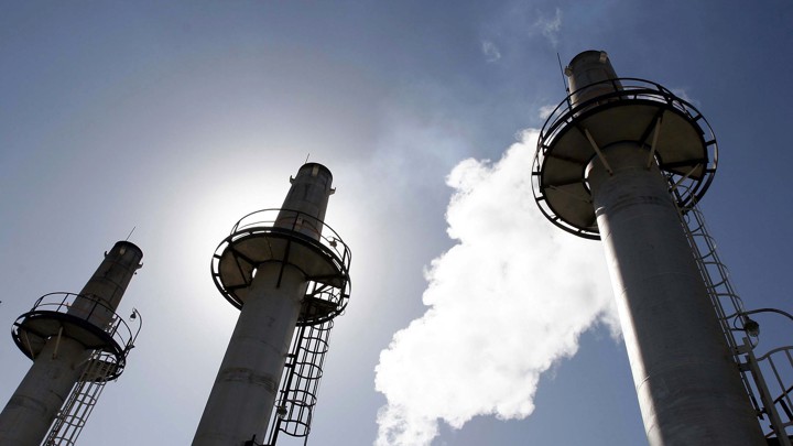 Three smokestacks backlit by the sun