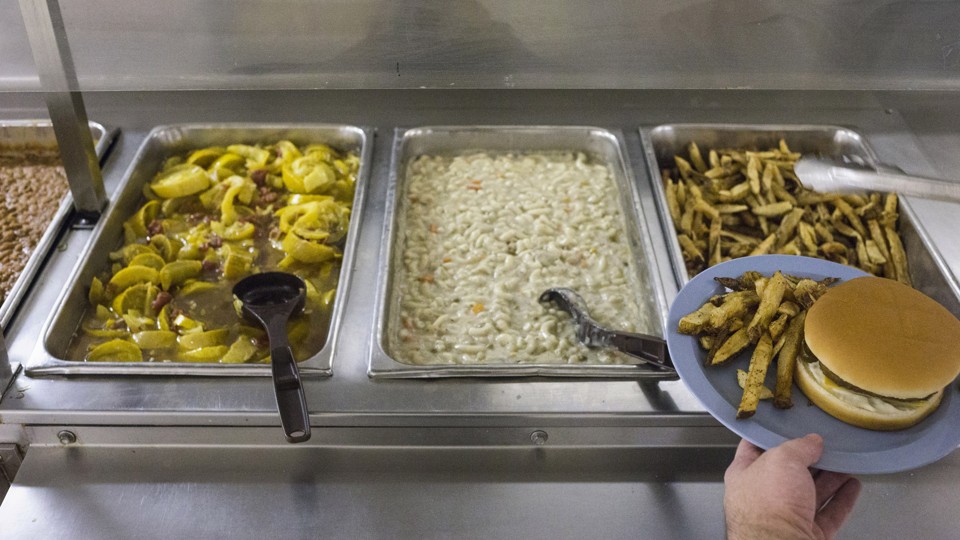 Hamburgers and fries being served in a cafeteria