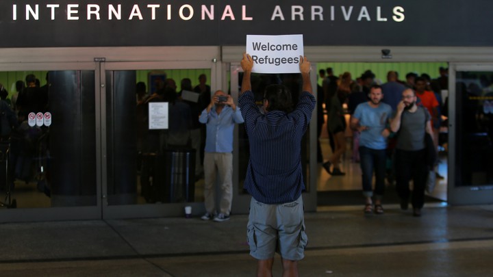 A man holds up a sign welcoming refugees at Los Angeles International Airport