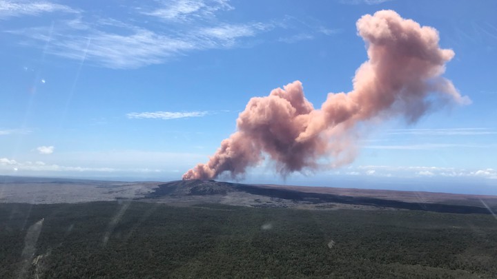 A plume of red-gray ash rises out of a Hawaiian volcano.