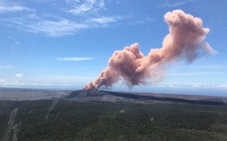 A plume of red-gray ash rises out of a Hawaiian volcano.