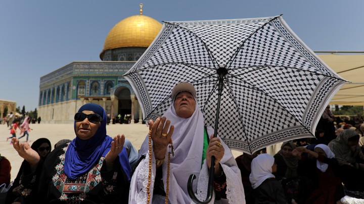 Women with an umbrella praying with their hands outstretched
