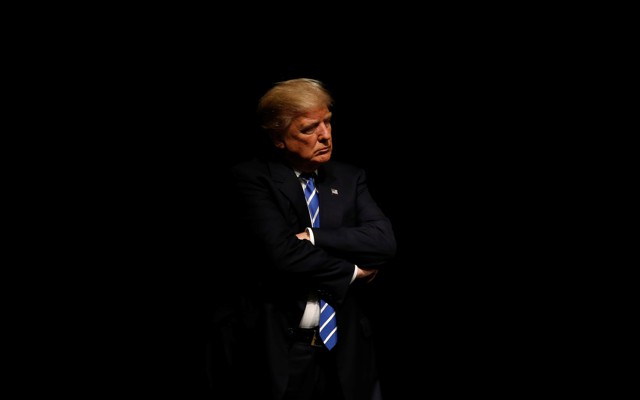 President Trump crossing his arms against a black background