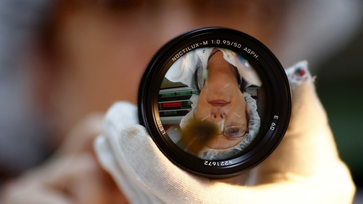 A technician is reflected in a 50-mm Leica Noctilux lens.