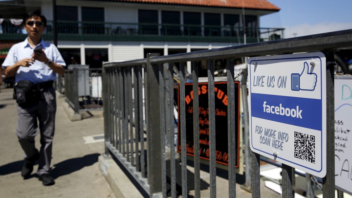 A man walks by a "Like Us on Facebook" sign