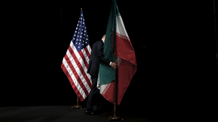 A man on a black stage removing the Iranian flag