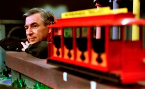 Fred Rogers resting near a trolley on a TV set