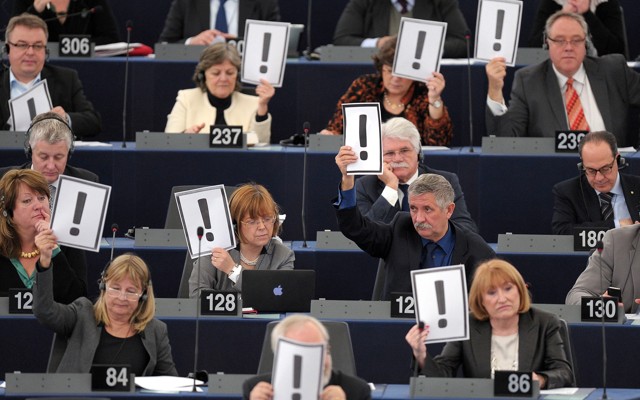 Men and women hold placards bearing an exclamation mark
