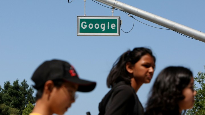 People walk past a street sign that reads "Google."