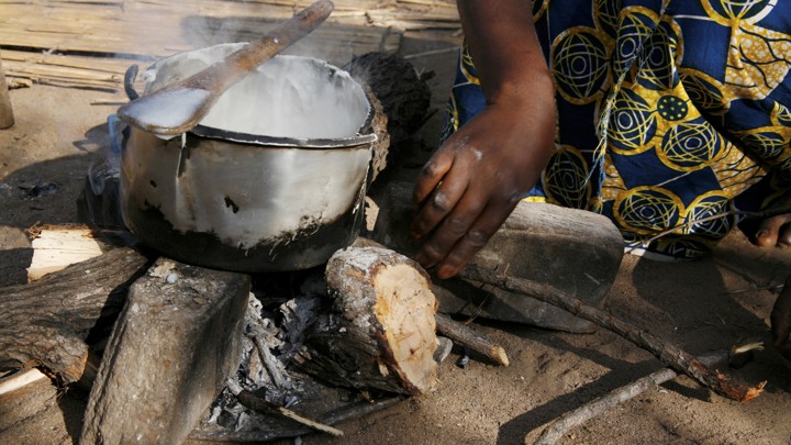 A silver, old, cracked saucepan rests on an open fire