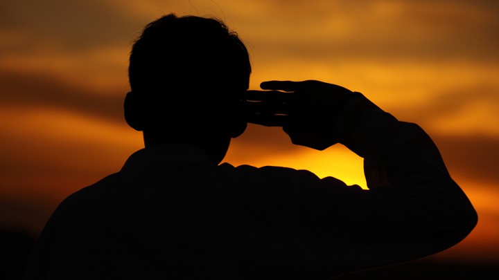 A boy salutes at sunset