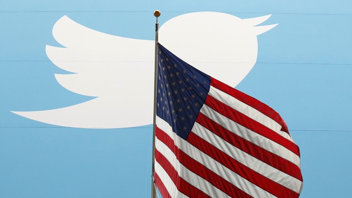 The Twitter logo behind a U.S. flag