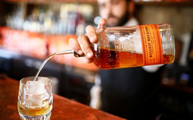 A bartender pours a glass of bourbon whiskey