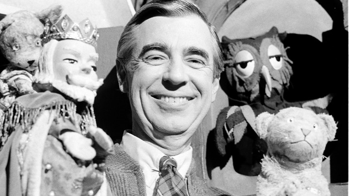A photo of Fred Rogers holding a few puppets.