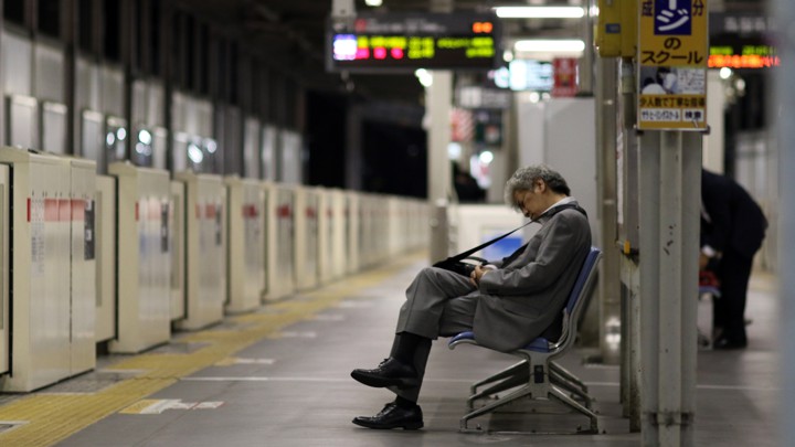 A man in business attire sleeps on a subway bench