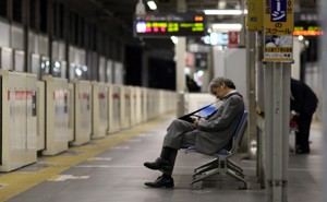 A man in business attire sleeps on a subway bench