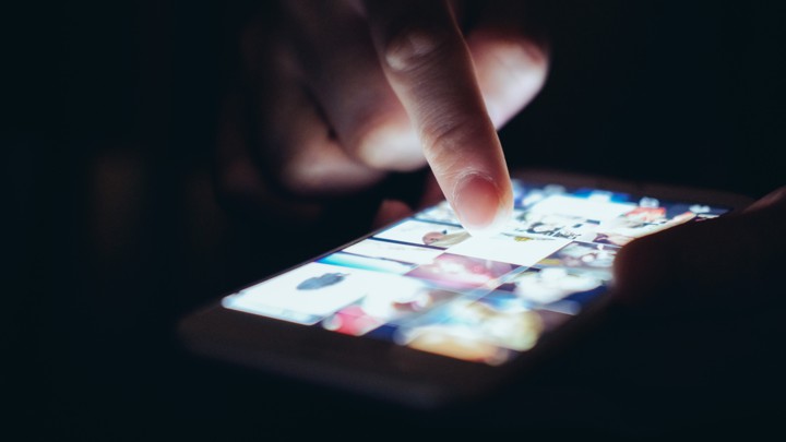 A finger touches an illuminated phone screen