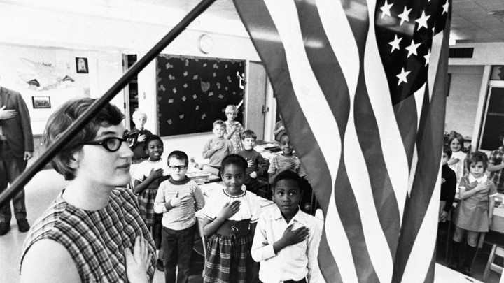 A teacher and her schoolchildren pledging allegiance to the American flag