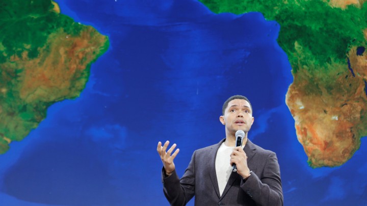 Trevor Noah stands in front of a map of Africa while speaking at a Gates Foundation event.