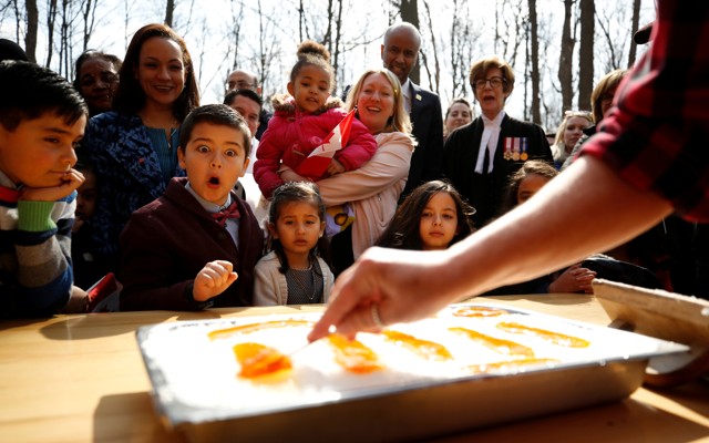 New Canadian citizens react as maple taffy is prepared following a citizenship ceremony in 2018