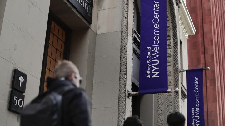 Students walk along a street with NYU banners