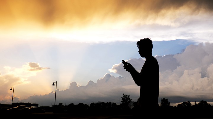 A teenager looks at their cell phone