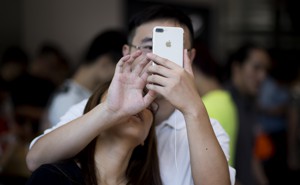 A woman leans on a man's shoulder, looking up on a phone in his hand