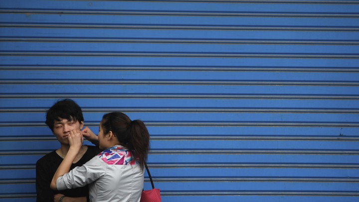 A woman pops a pimple on her boyfriend's face